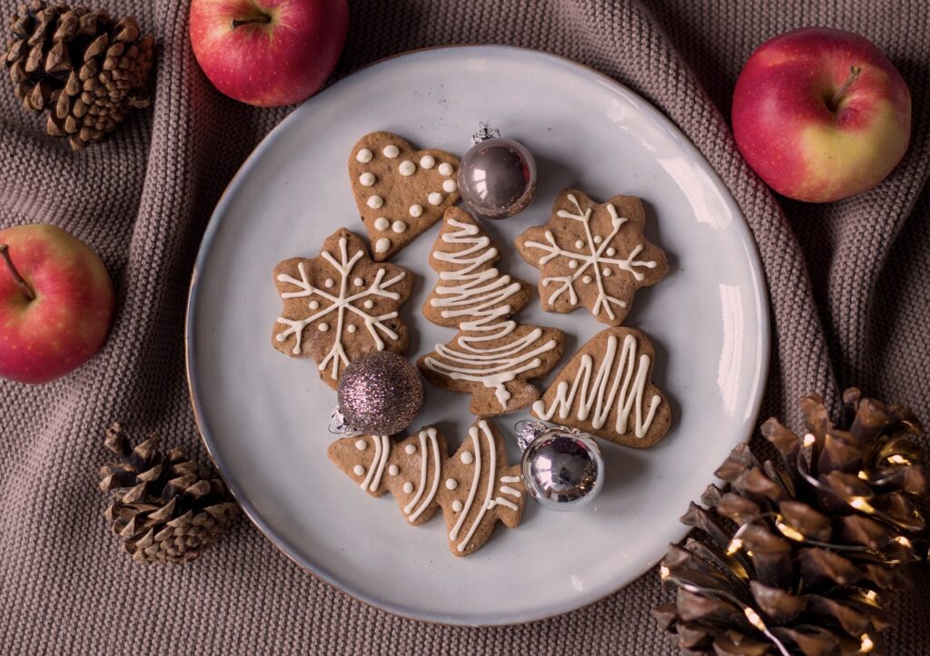 Galletas navideñas decoradas en plato blanco con manzanas.